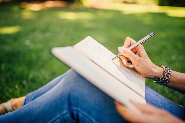 Eine Frau sitzt im Freien und schreibt in ein Notizbuch